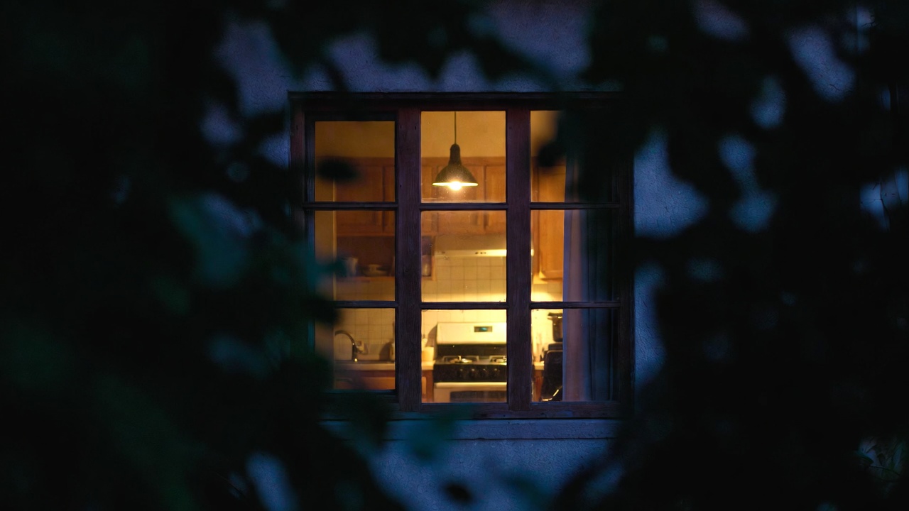 Warm kitchen light seen through a window at night